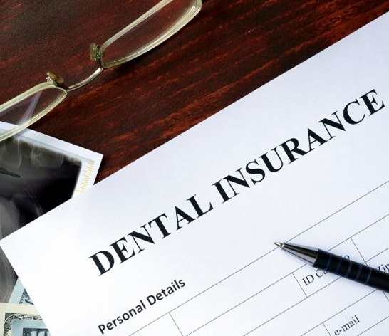 Paper that says “dental insurance” sitting on a desk with glasses