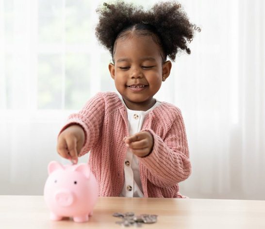 child inserting coins into a piggy bank